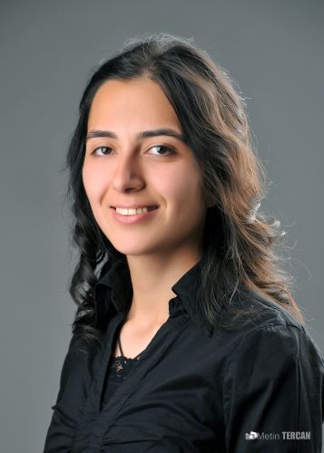 A smiling young woman looks at the camera against a gray background