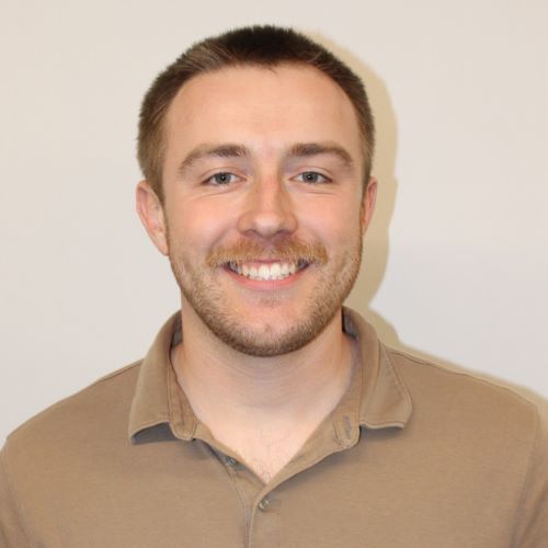 A young man smiles at the camera