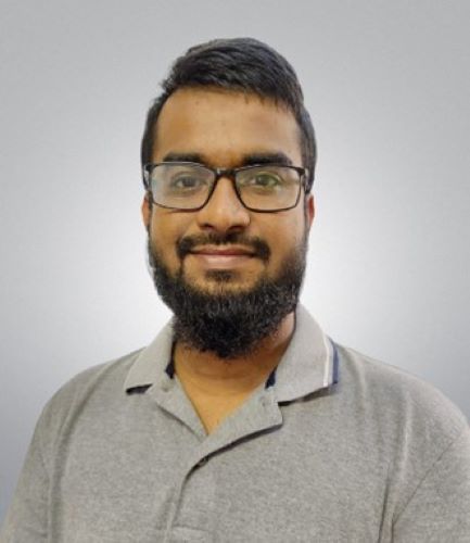 A young man smiles at the camera against a gray background