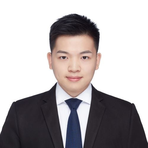 A young man in a suit smiles at the camera