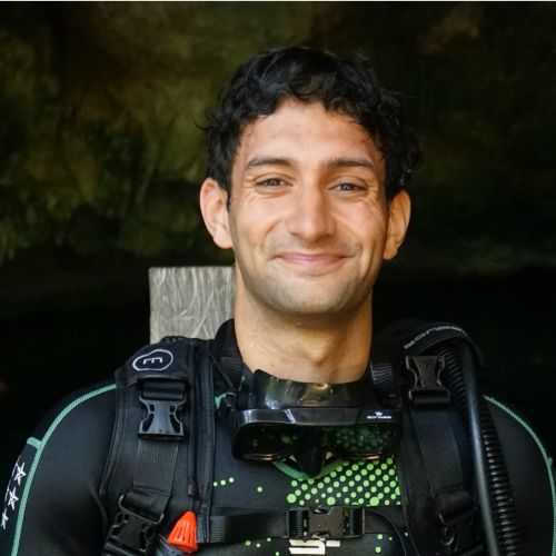 A young man smiles at the camera