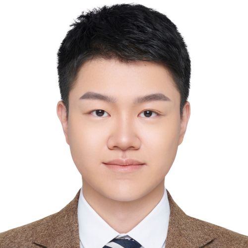 A young man in a suit grins at the camera