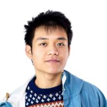 A young man against a white background looks at the camera