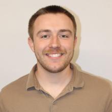 A young man smiles at the camera