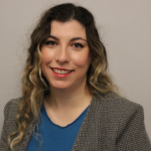 A young woman in professional dress smiles at the camera