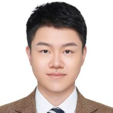 A young man in a suit grins at the camera